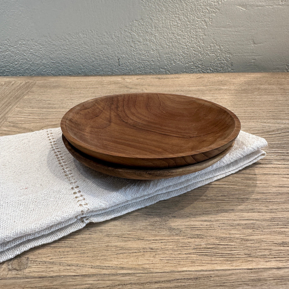 Two small teak plates on cloth napkin.