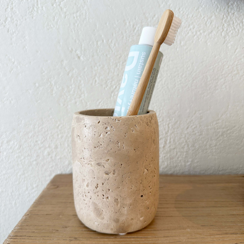 Travertine Toothbrush Holder with Toothpaste tube and wooden toothbrush.