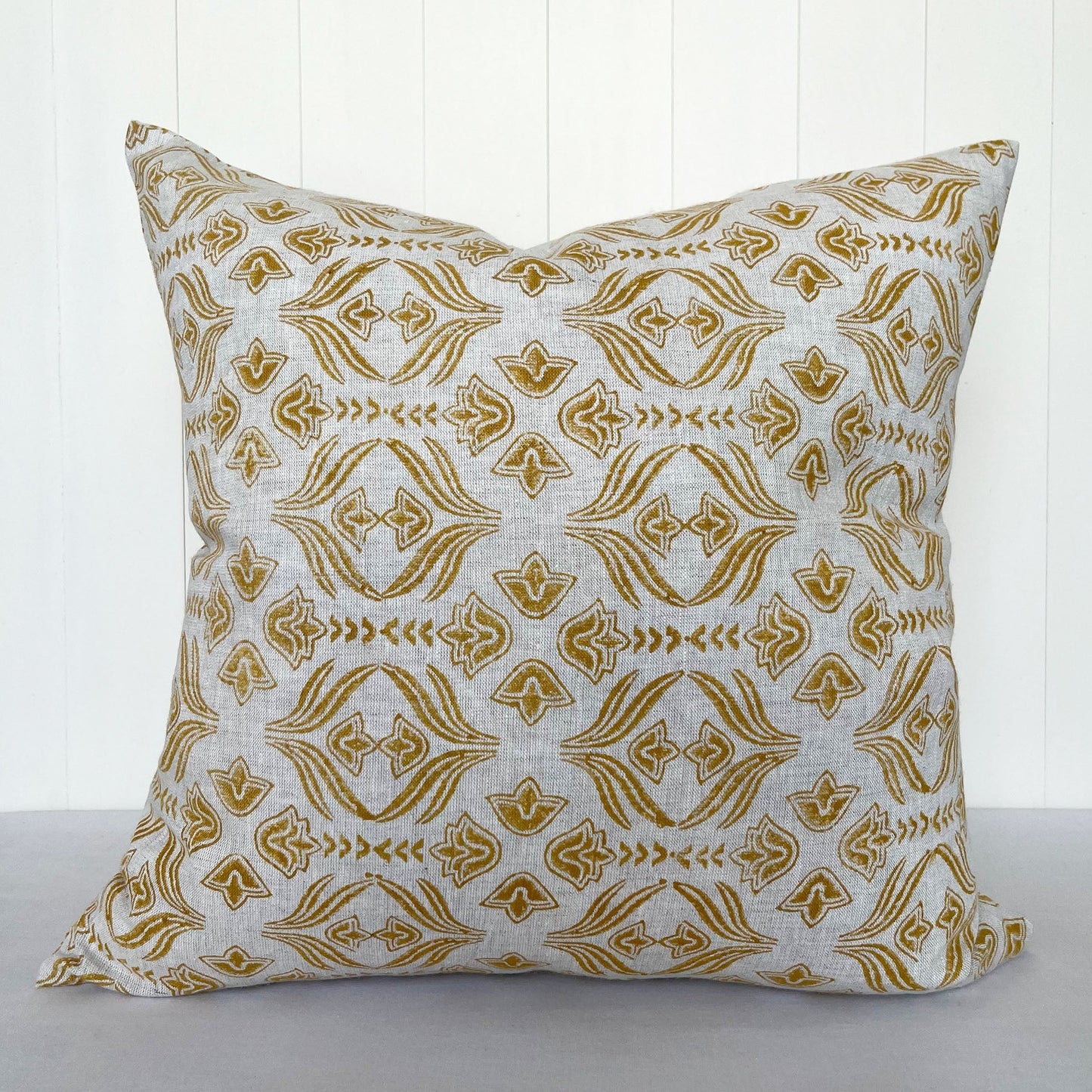 Square throw pillow featuring hand block printed floral pattern. Natural colored linen is stamped with a golden yellow pattern.