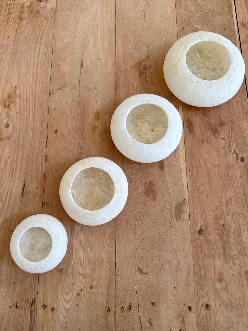 4 different sized Disc Shaped Votive placed on a wooden surface
