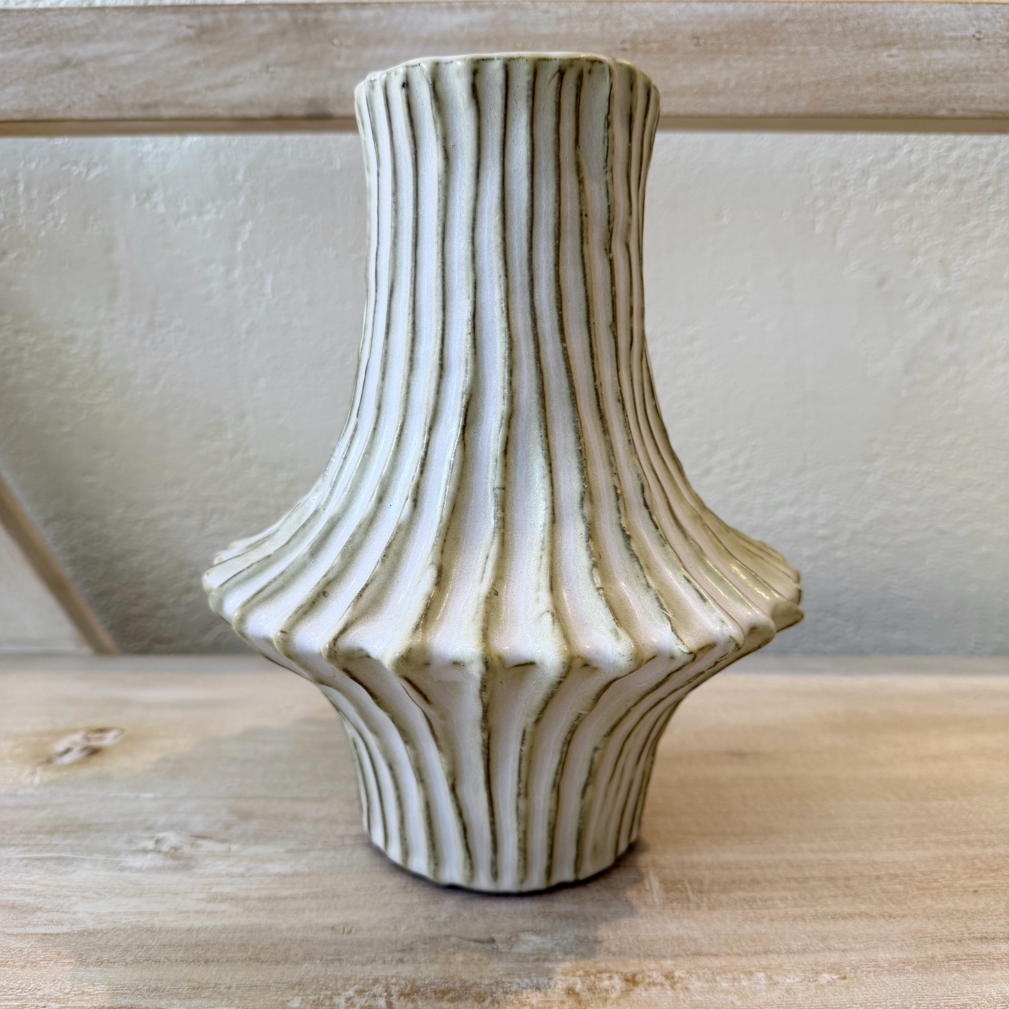 Decorative ceramic vase with ribbed design on a wooden surface