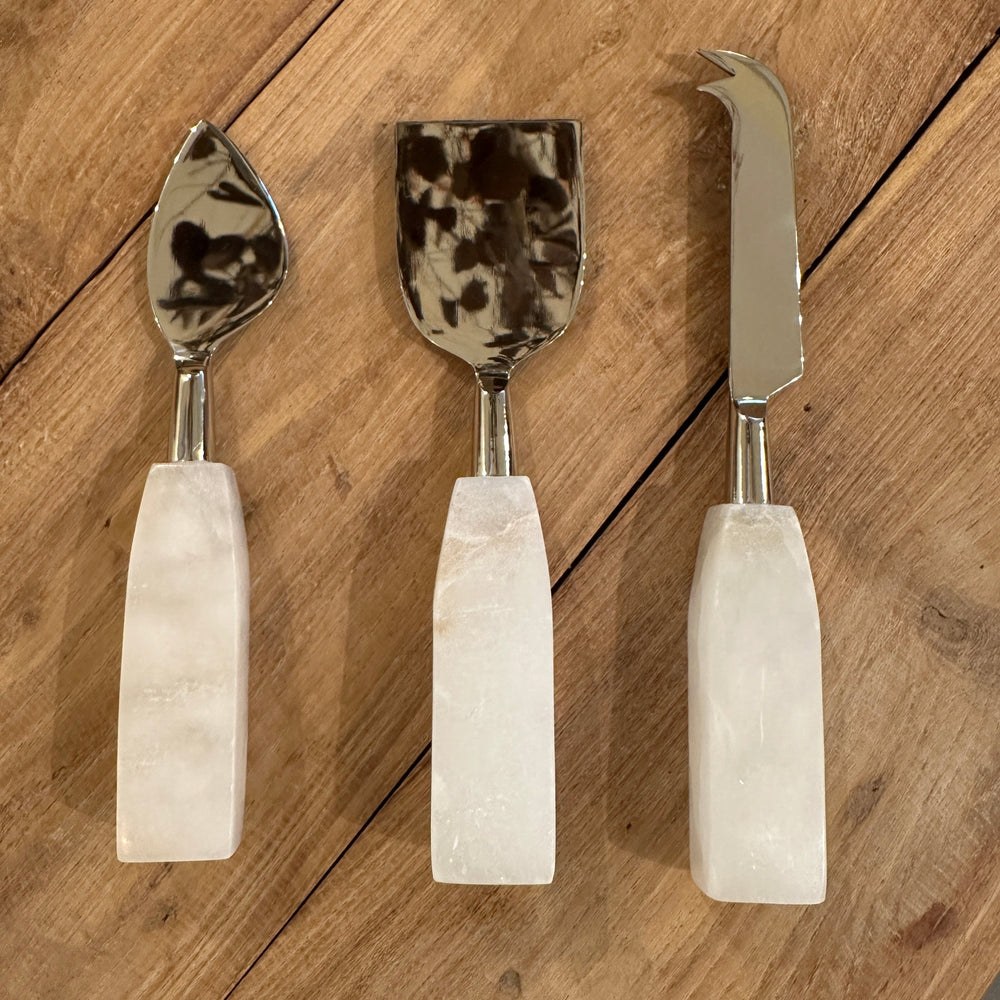 3 cheese knives on a wooden table 