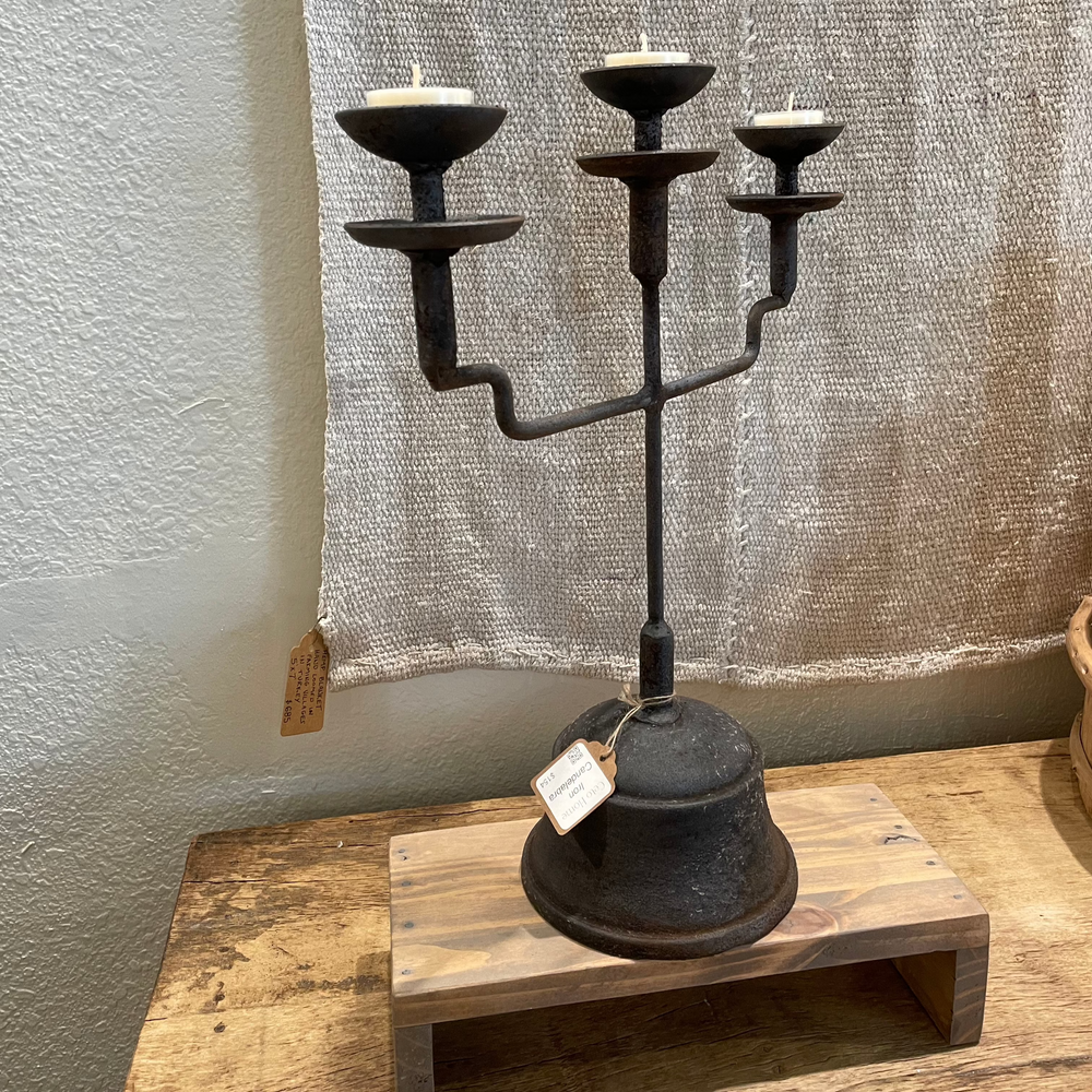 An aged iron Candelabra with a linen blanket on the wall