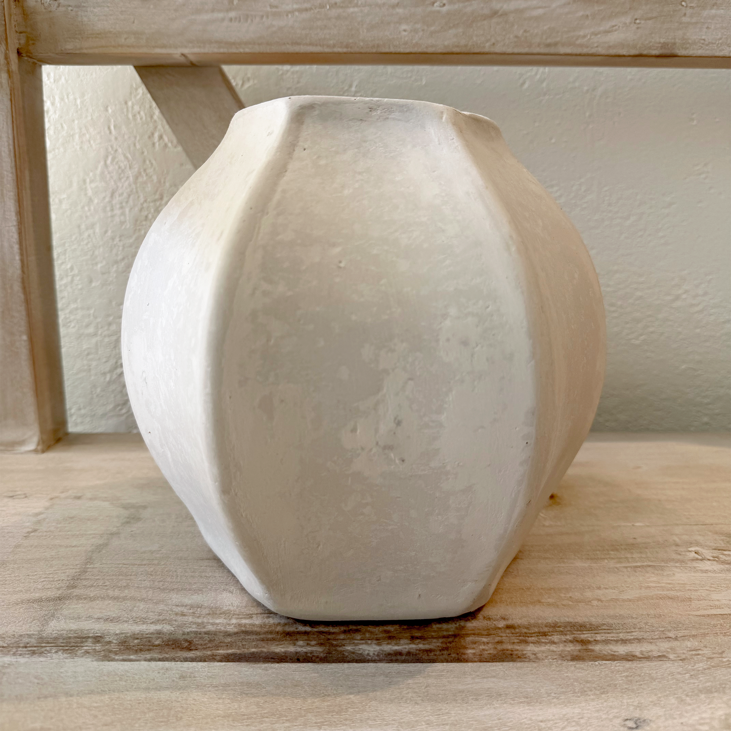 White paper mache vase on a wooden surface with a neutral background