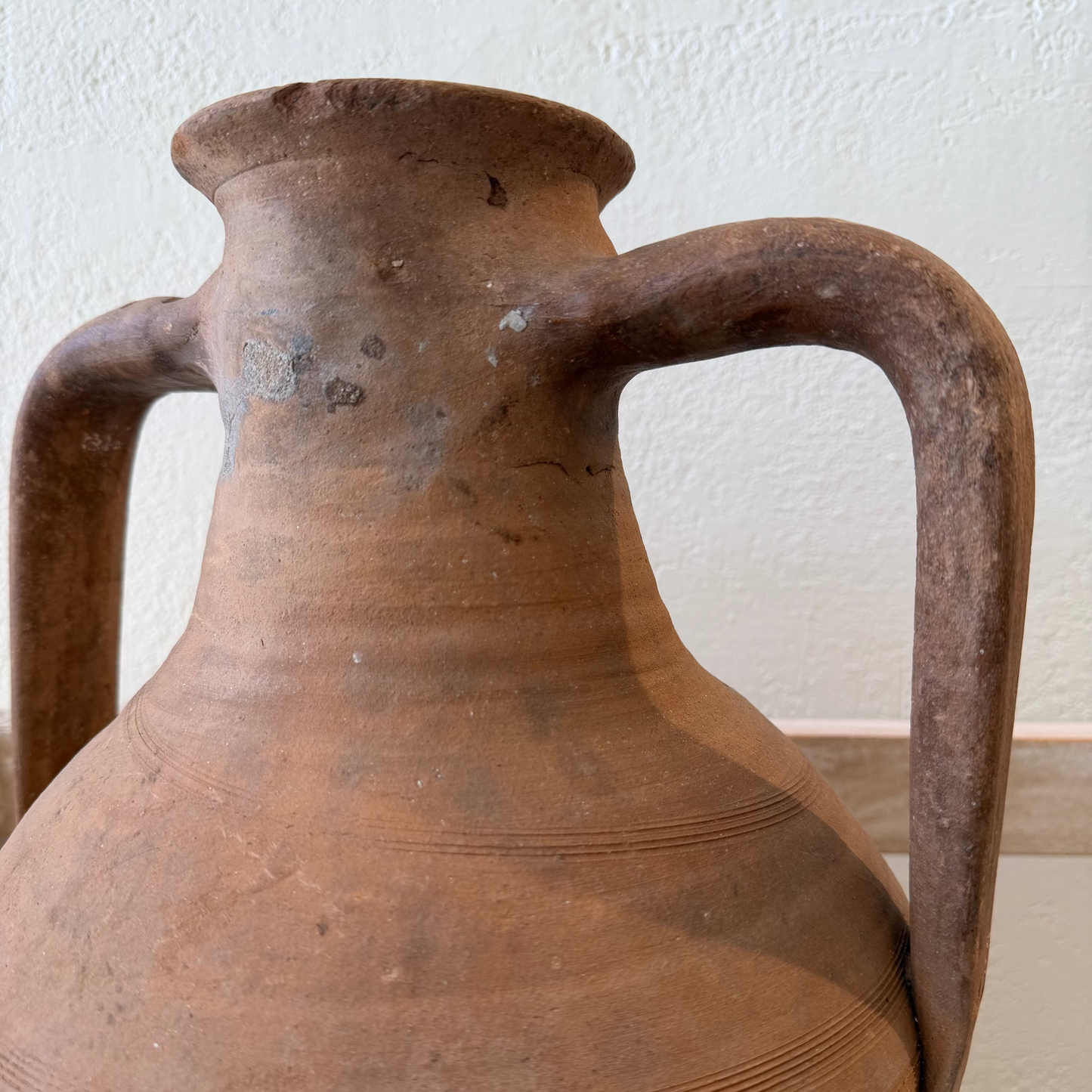Brown ceramic jar with two handles on a white background
