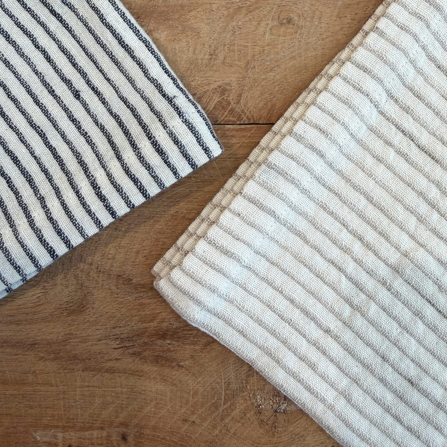 
                  
                    Two striped rugs on a wooden floor, one with black and white stripes and the other with beige and white stripes.
                  
                