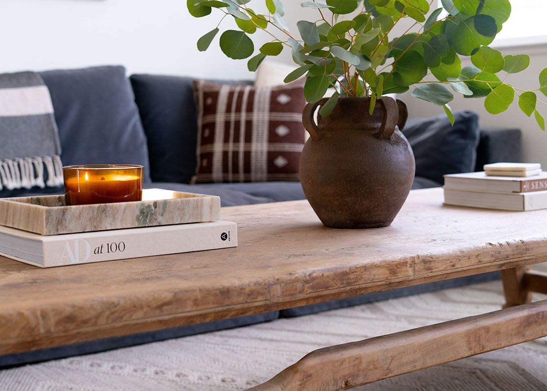 Wooden coffee table with a vase, books, and candle on a living room setting
