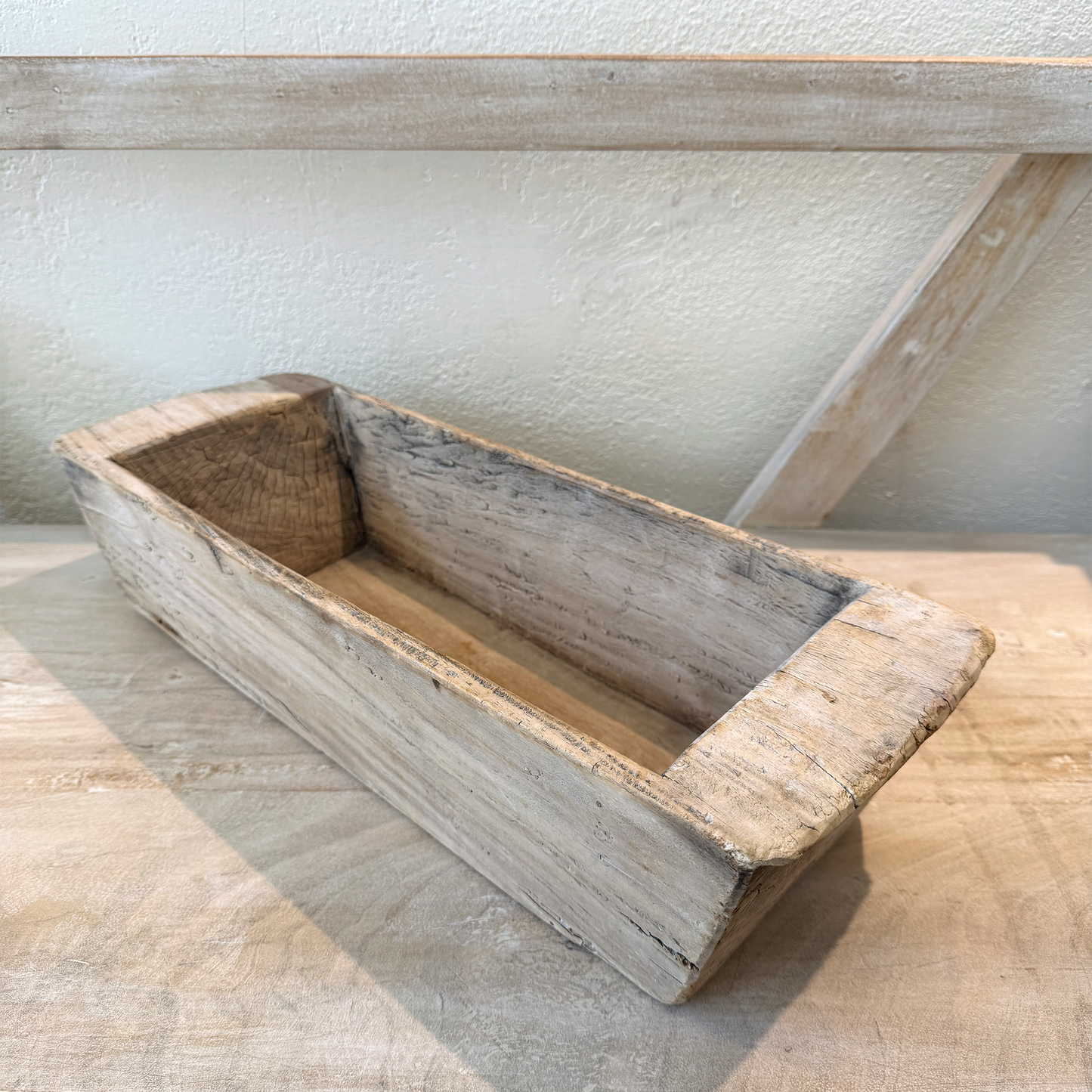
                  
                    Wooden bread loaf pan on a wooden surface with a white wall background
                  
                