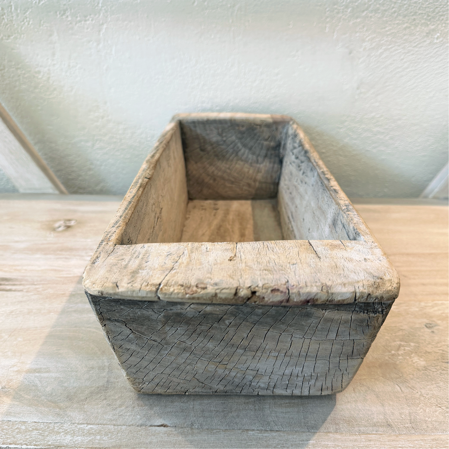 Wooden planter box on a wooden surface with a neutral background