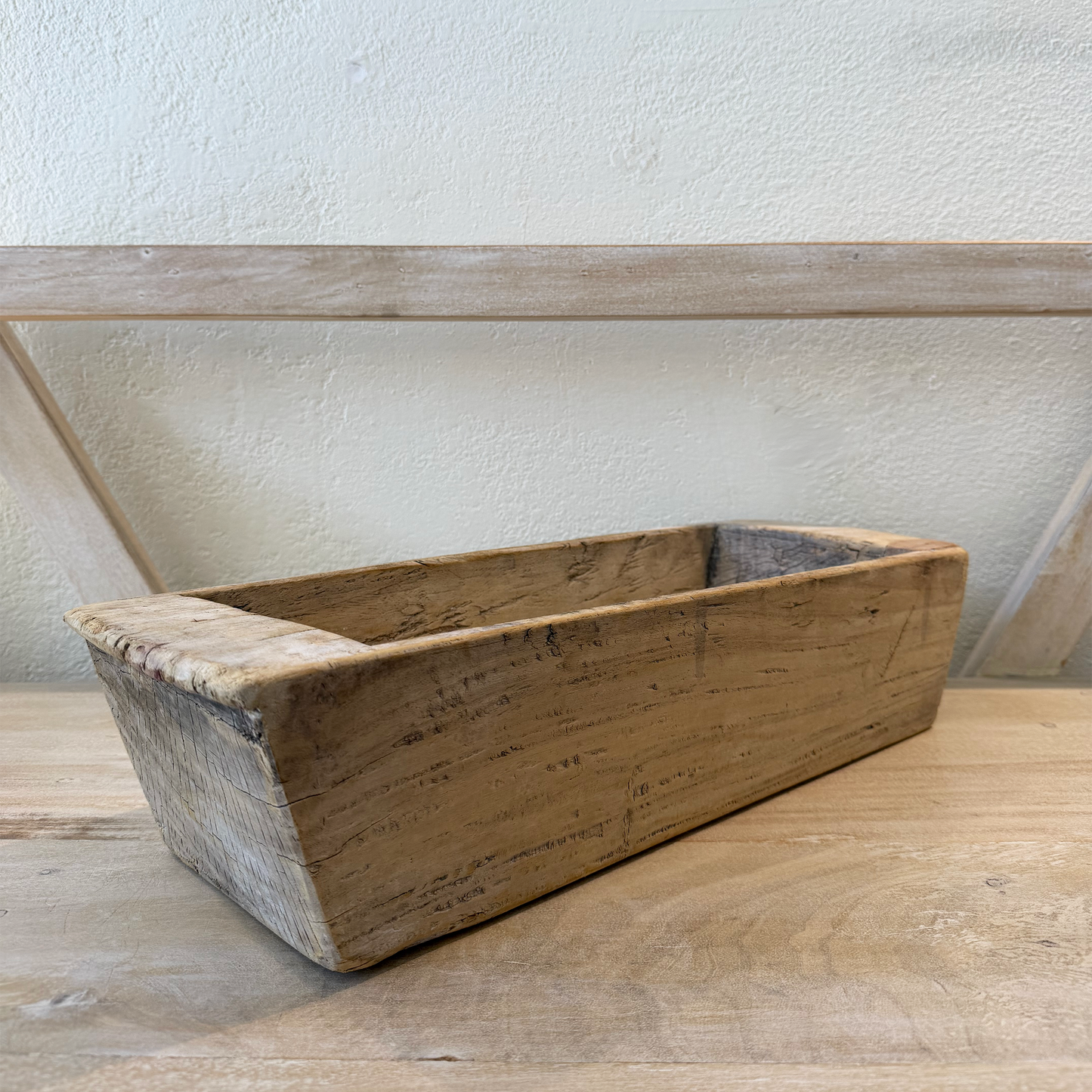 Wooden bread loaf pan on a wooden surface with a white wall background