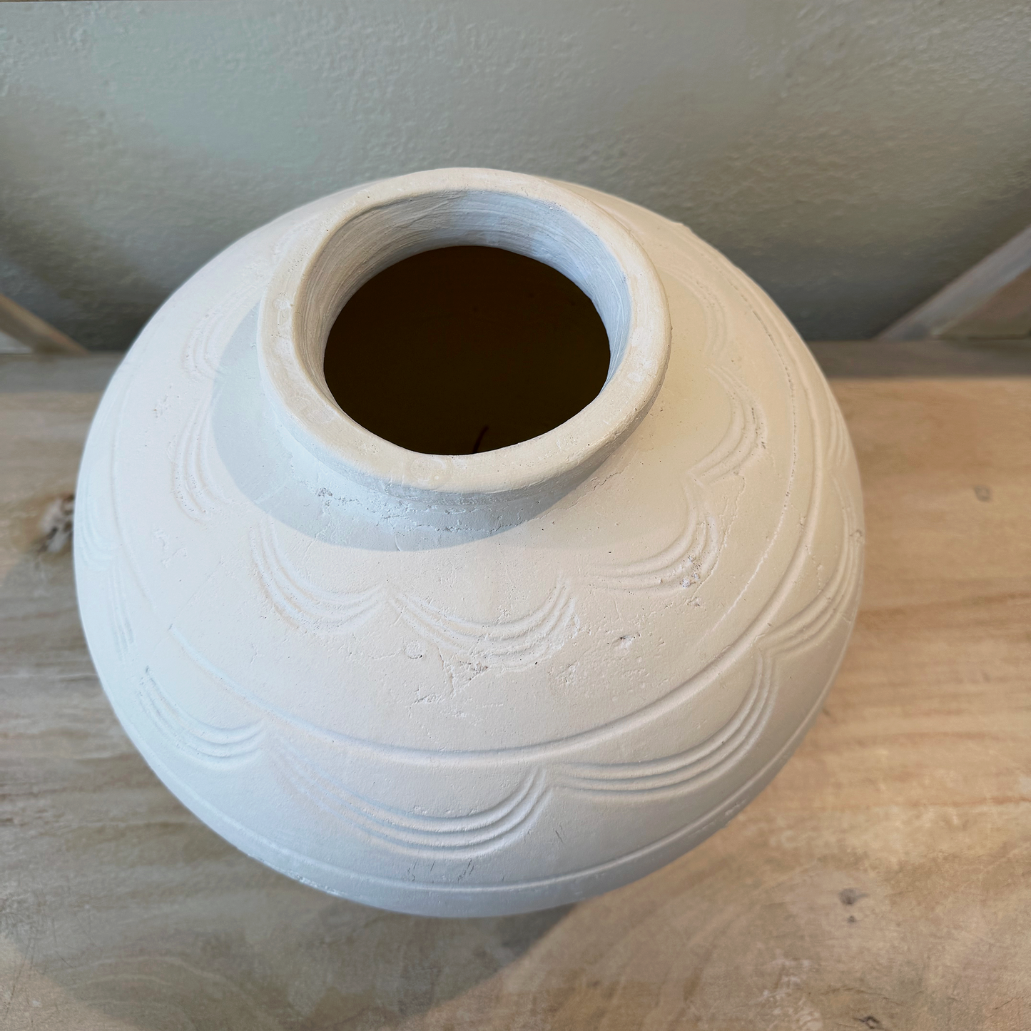 White ceramic vase with textured design on a wooden surface