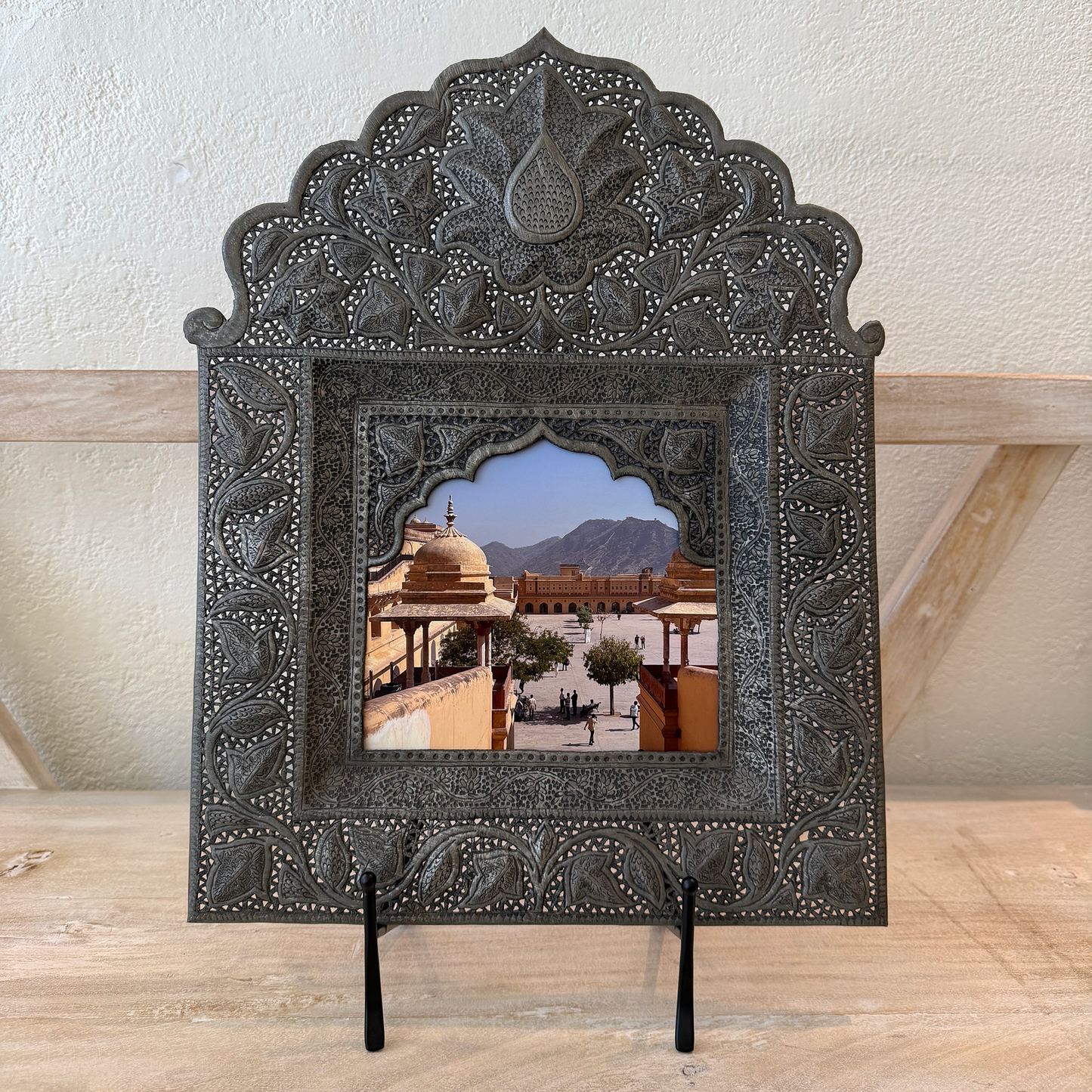 Decorative metal frame with intricate designs on a wooden surface.