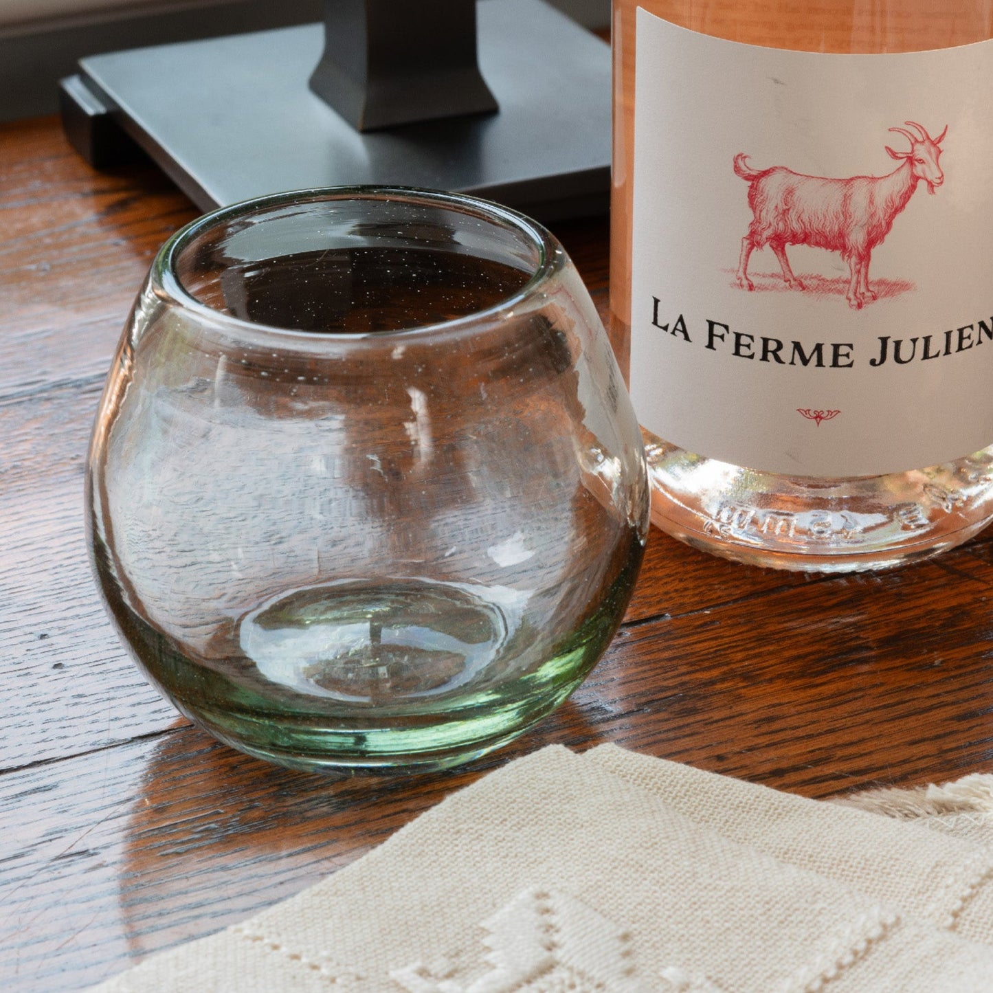 
                  
                    A stemless hand blown wine glass. Displayed next to a bottle of rose
                  
                