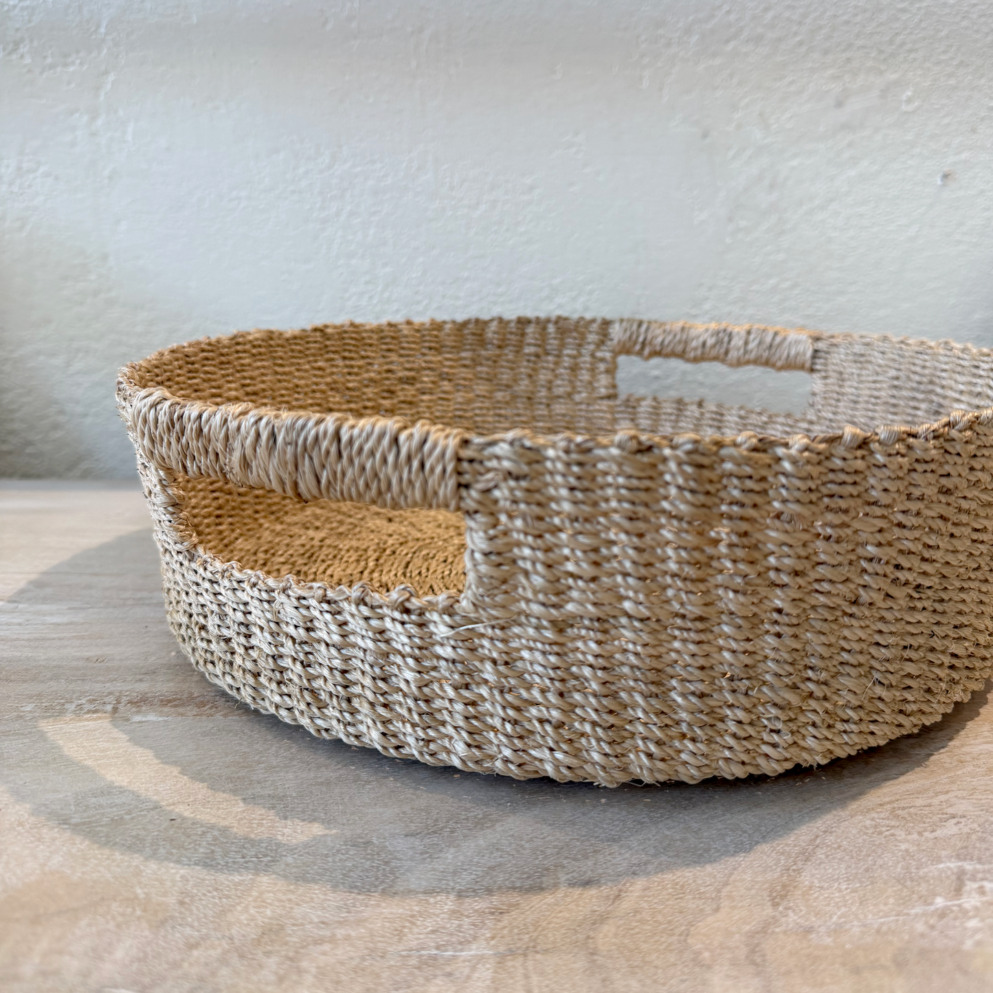 Woven basket with a handle on a light wooden surface