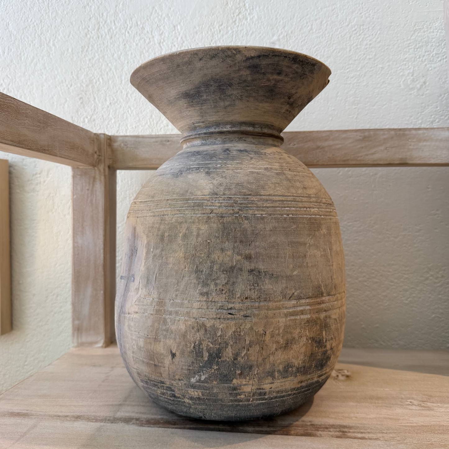 Brown ceramic vase on a wooden surface with a light background
