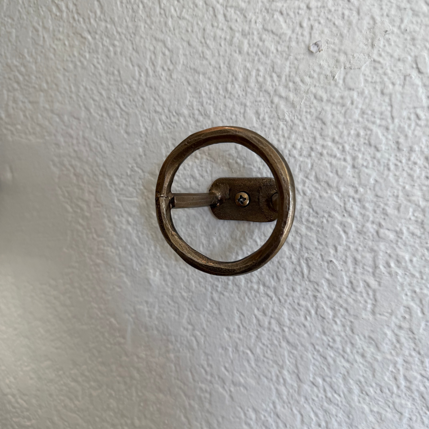 
                  
                    Bronze wall-mounted handle on a textured white wall
                  
                