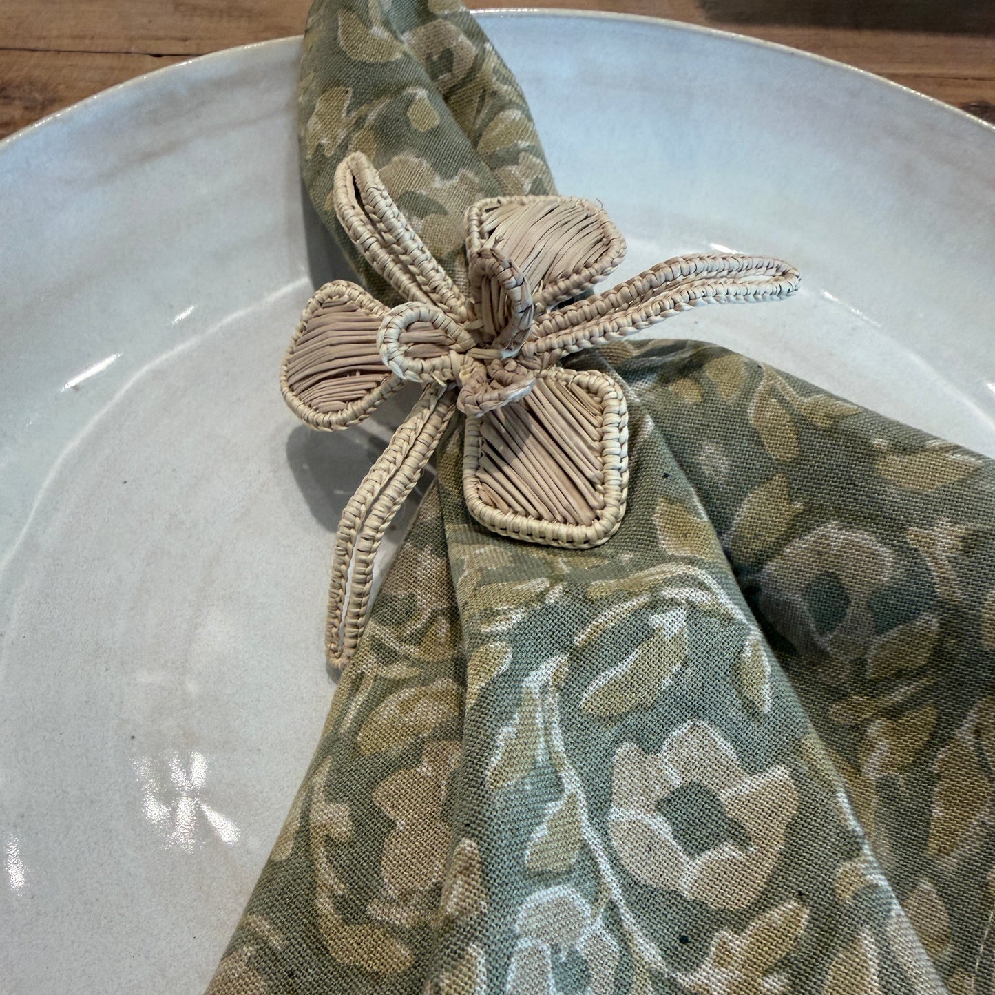 
                  
                    Napkin with floral pattern and decorative napkin ring placed on a white hand made ceramic plate in the petaluma store
                  
                