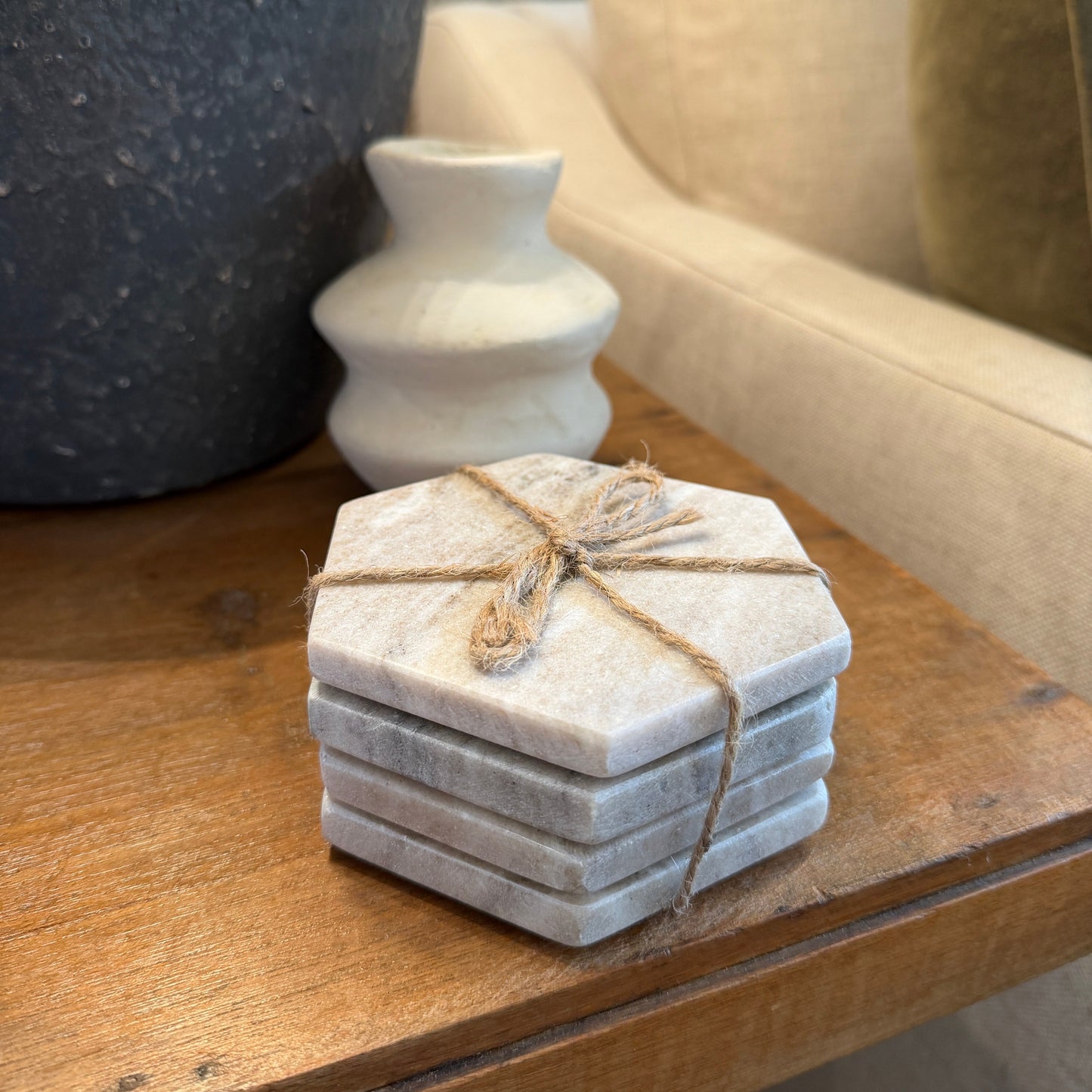 Stack of hexagonal stone coasters tied with twine on a wooden surface.