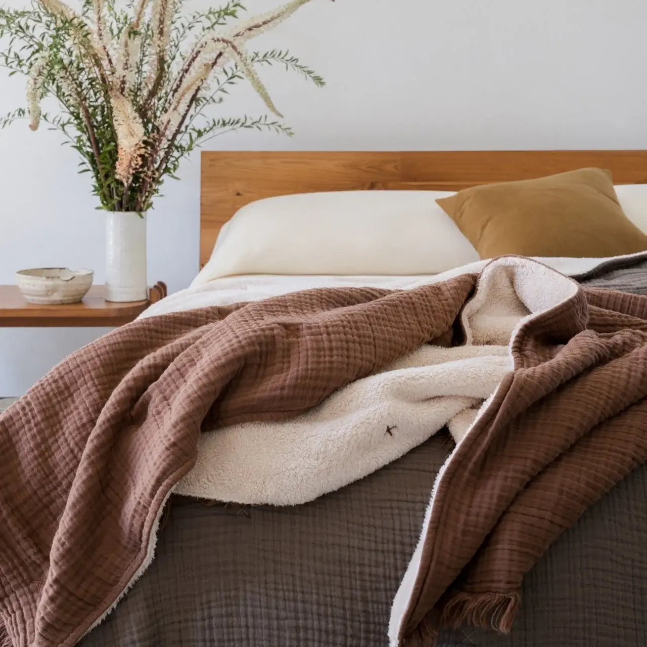 
                  
                    Bed with brown and beige blanket, white pillows, and wooden headboard in a bedroom setting.
                  
                