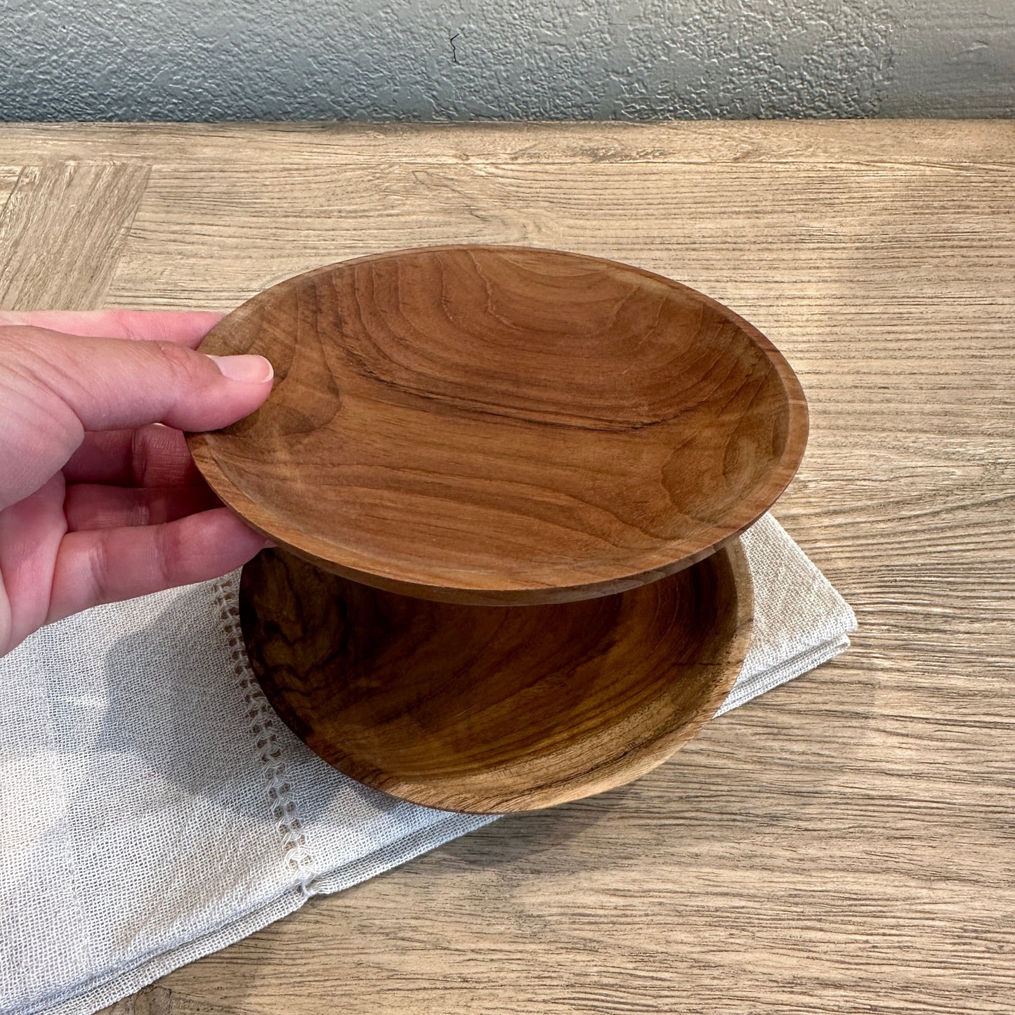 
                  
                    A designers hand holding the small teak  plate to show a sense of scale
                  
                