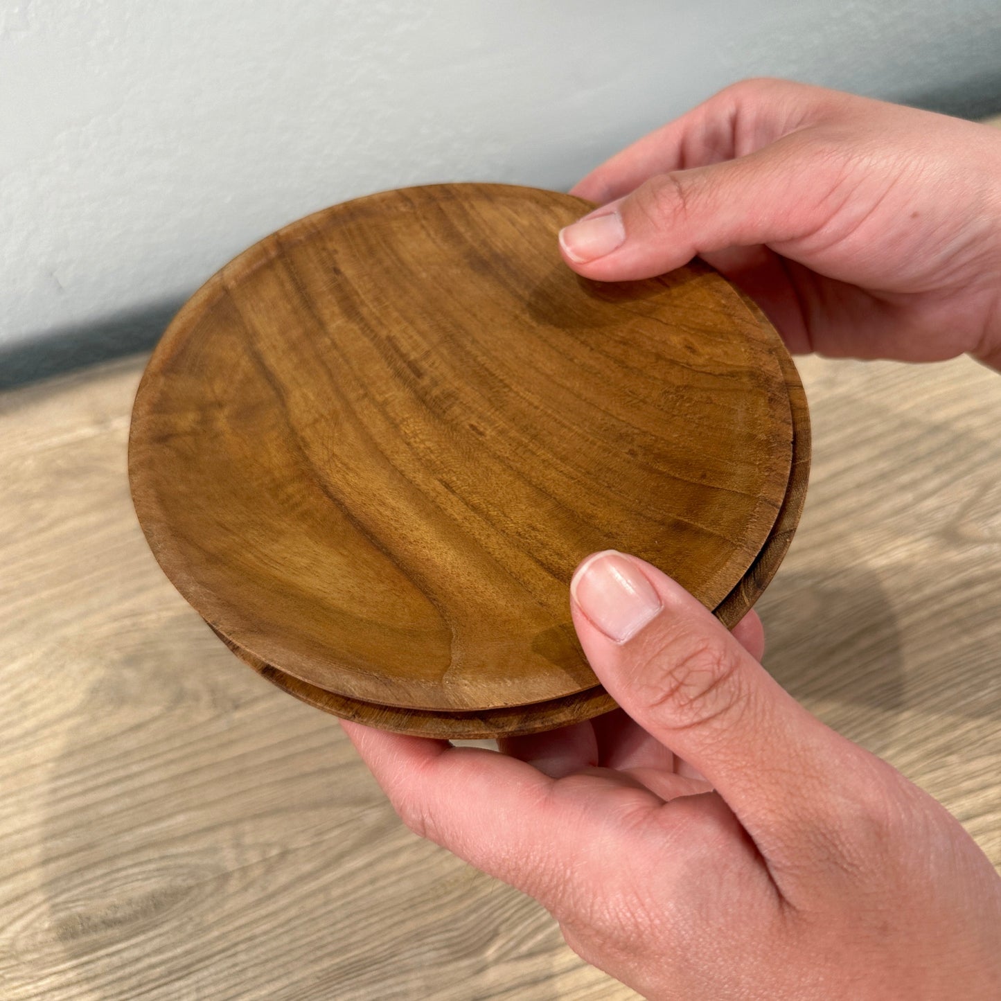 
                  
                    Two hands holding small wood dishes.
                  
                