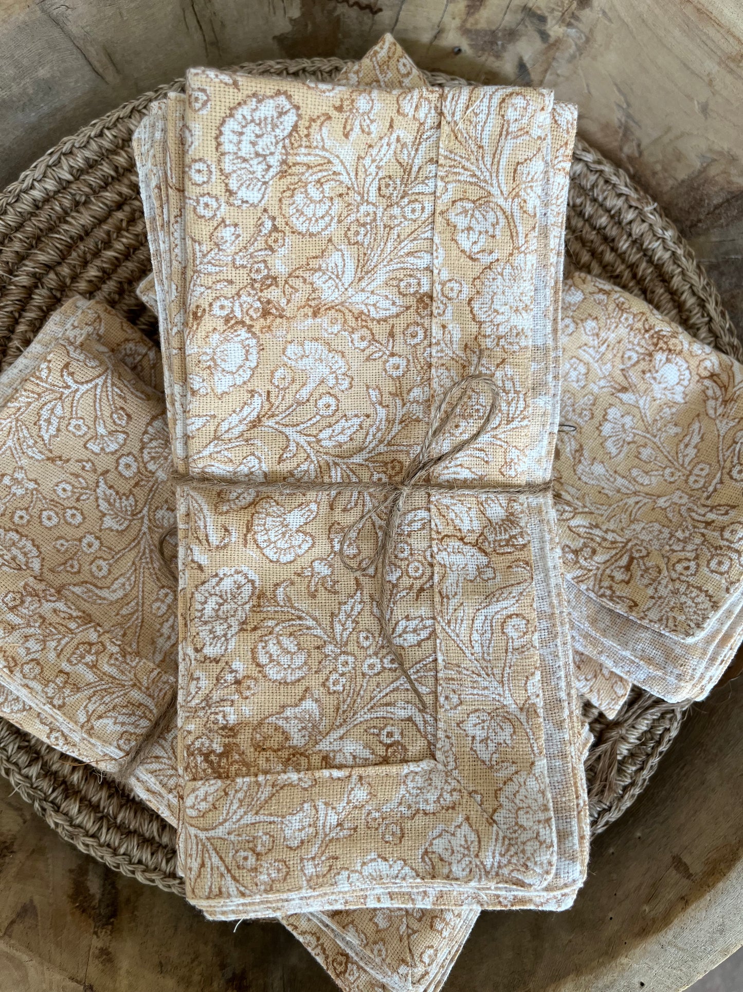
                  
                    Burnt Orange Floral Napkin. 3 stacks of 4 tied with some natural cord and placed on a hand made circular placemat in the Petaluma Store
                  
                