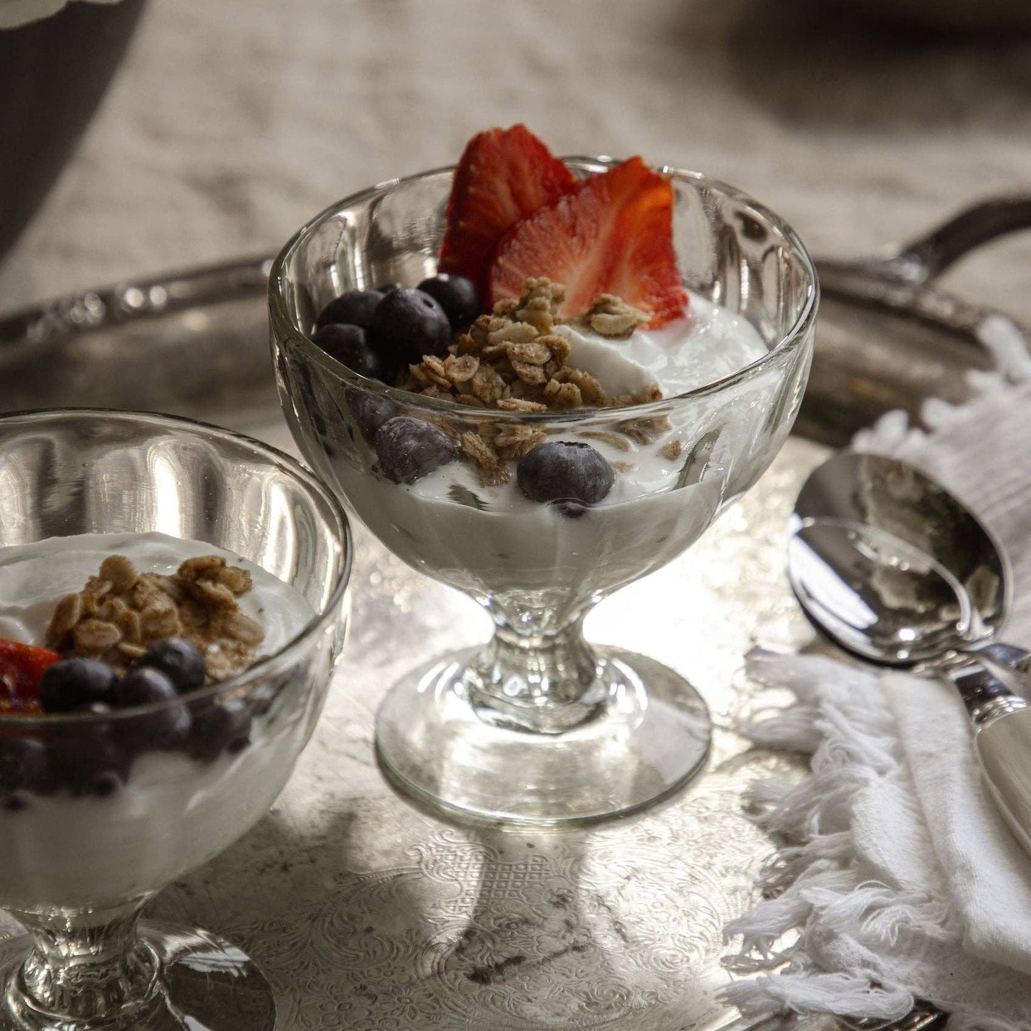 
                  
                    Parfait Glass with Yogurt and berries on a silver tray.
                  
                