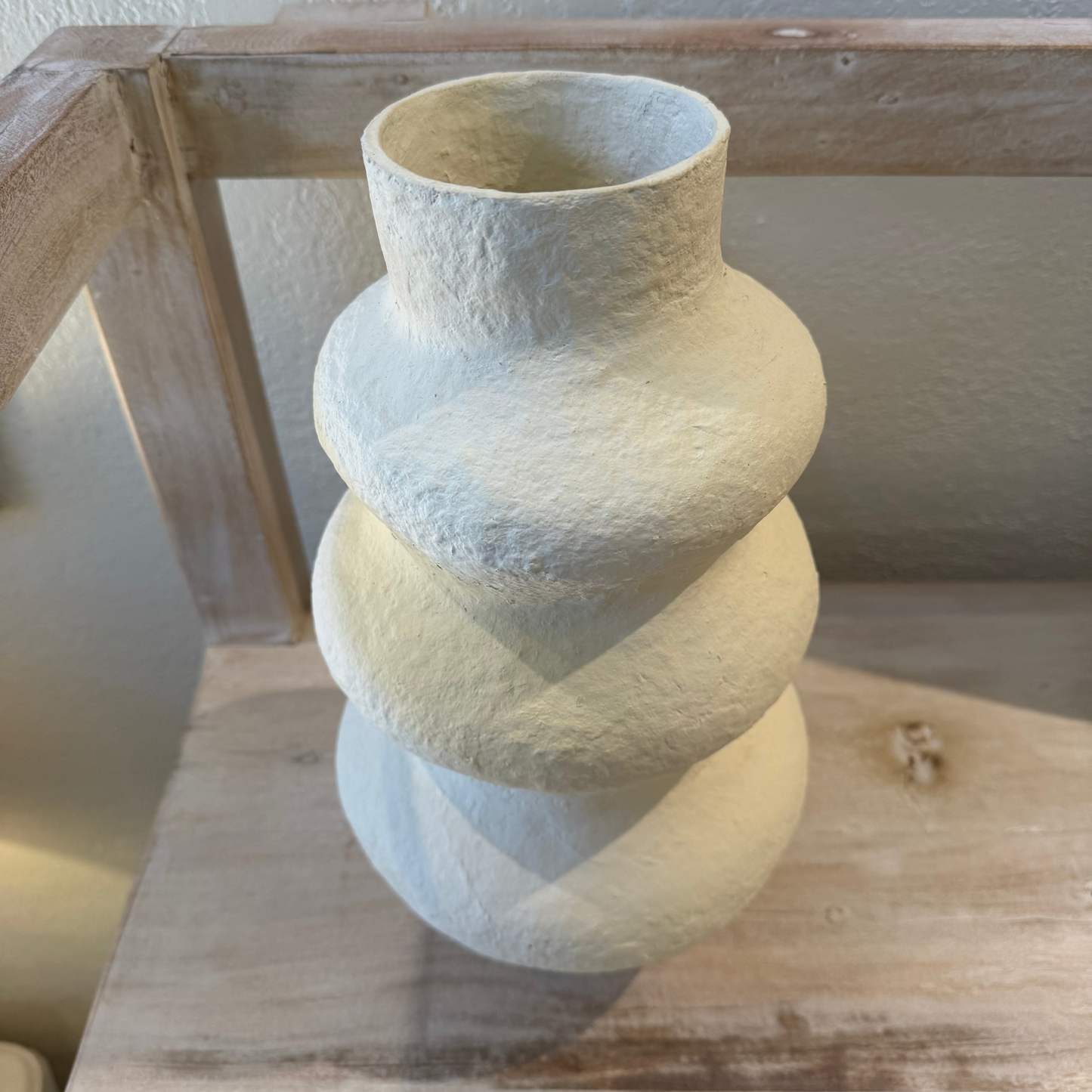Textured ceramic vase on a wooden surface with a neutral background