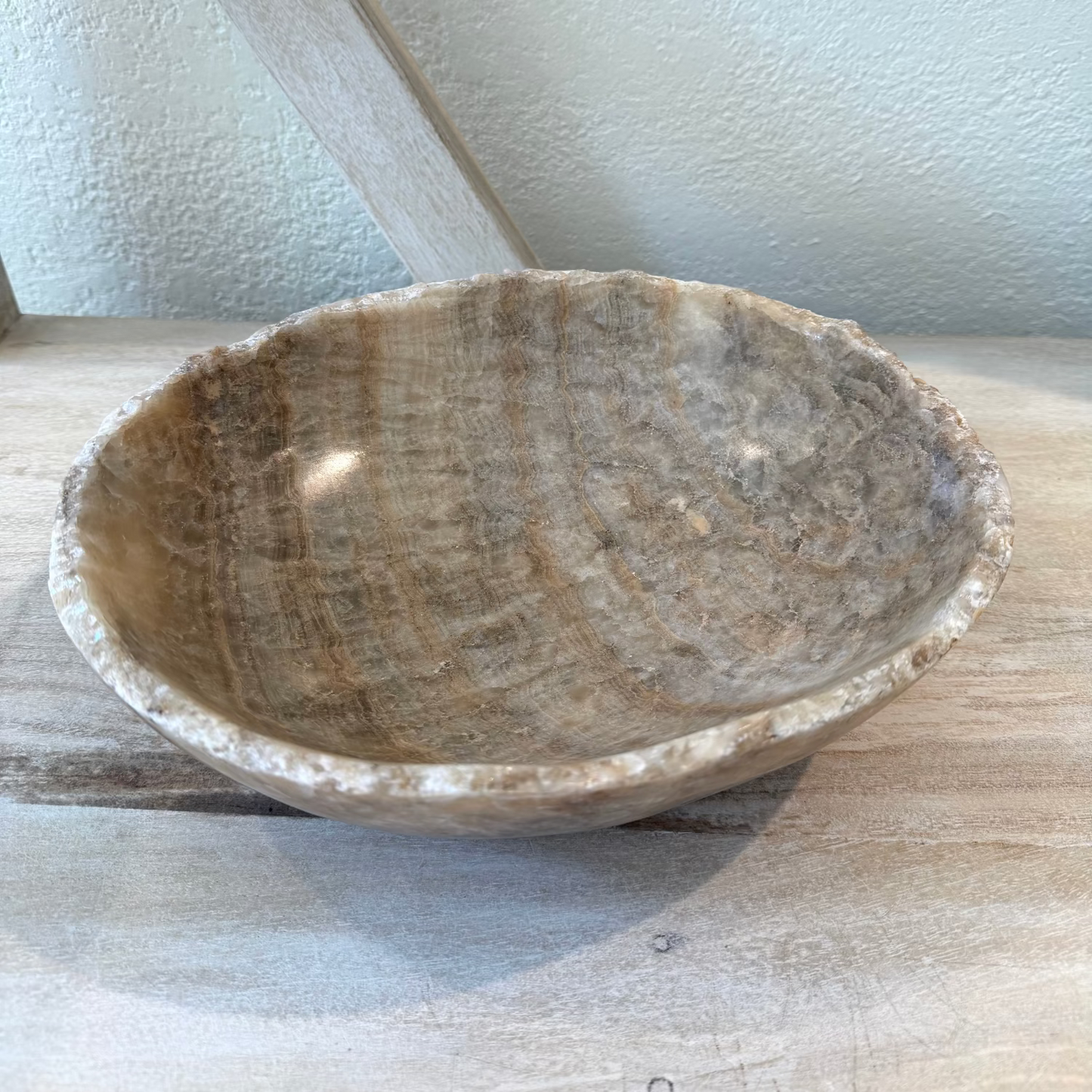 Brown stone bowl on a light wooden surface with a white wall background