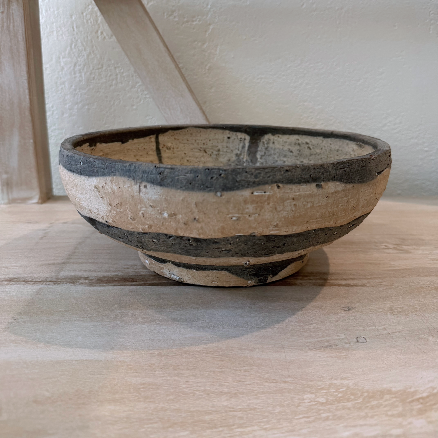 Ceramic bowl with black and beige design on a wooden surface