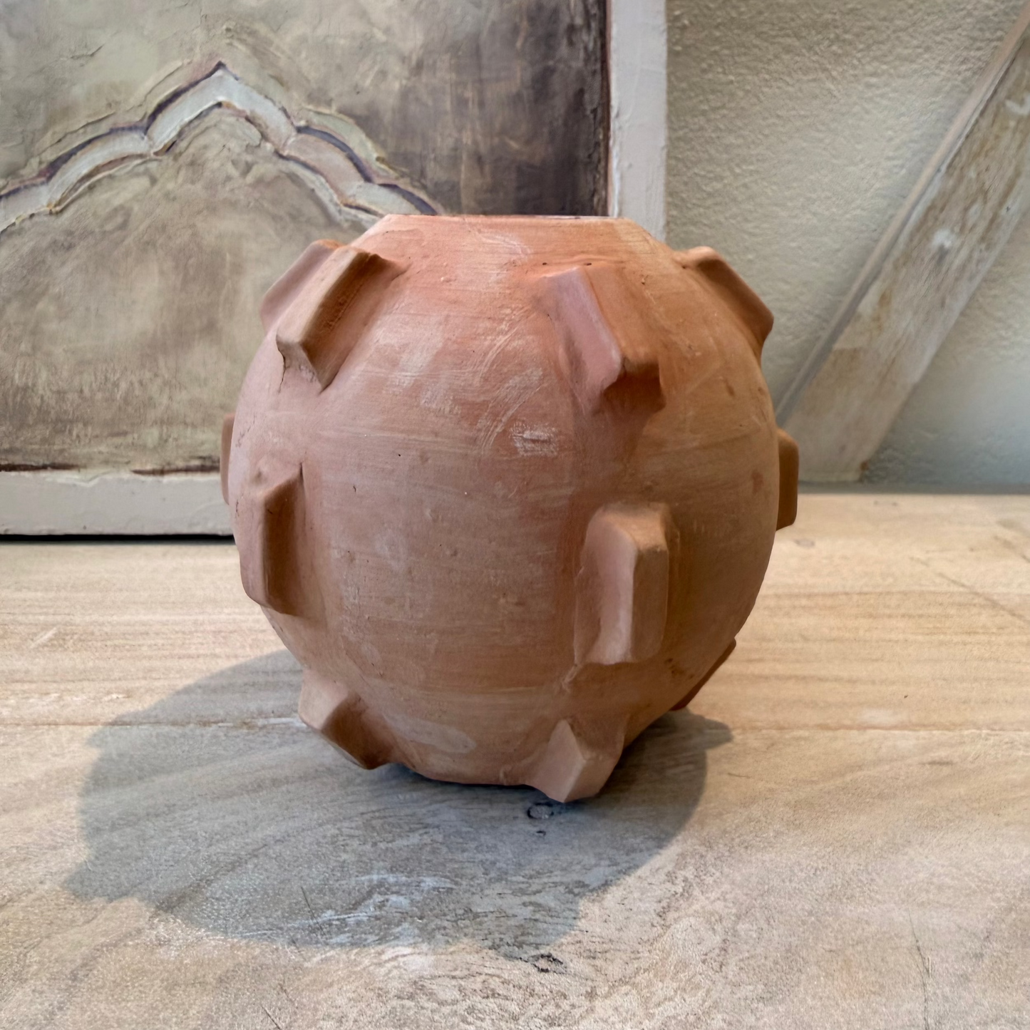 Terracotta pig-shaped planter on a stone surface with a textured wall background