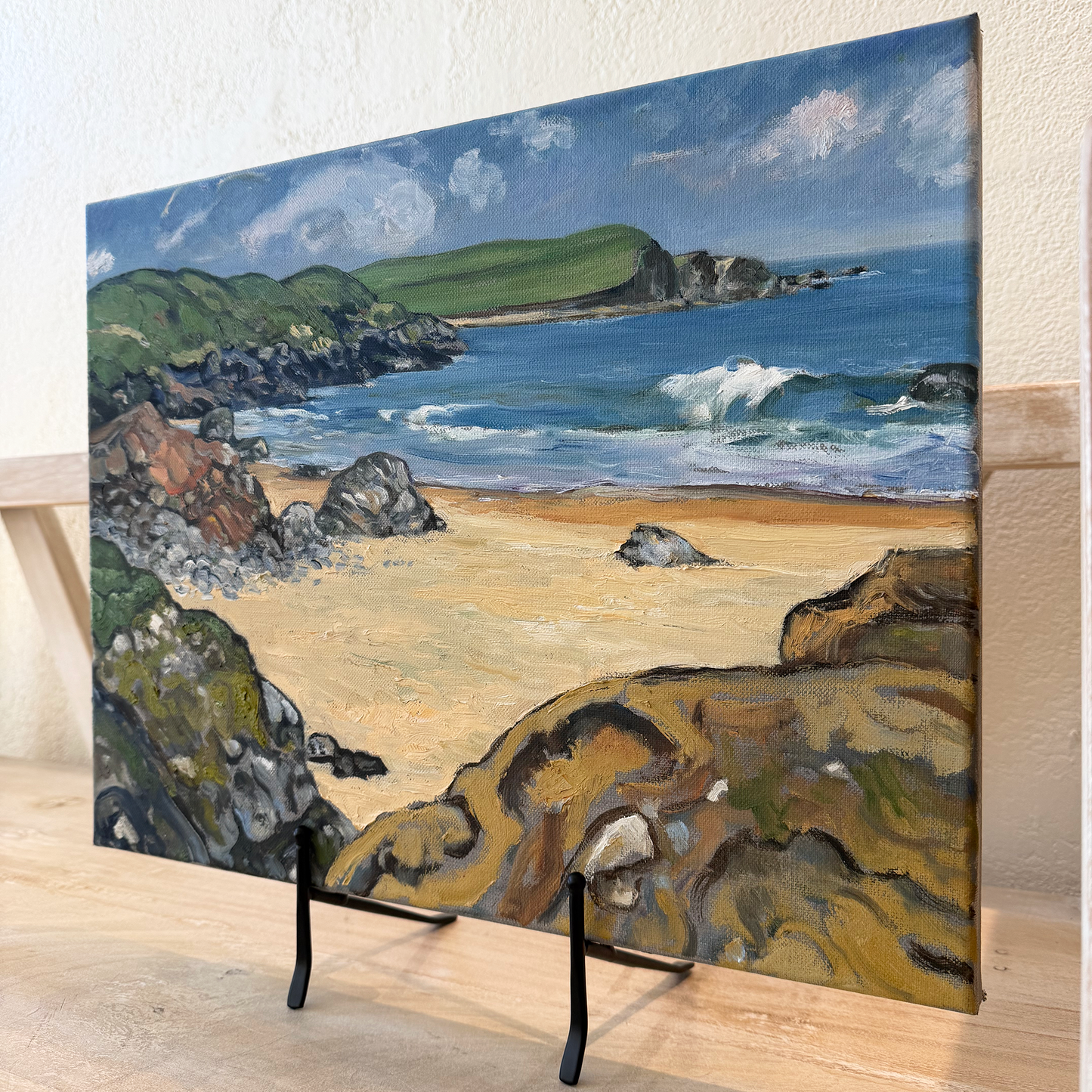 Painting of a coastal landscape on a stand with a white wall background